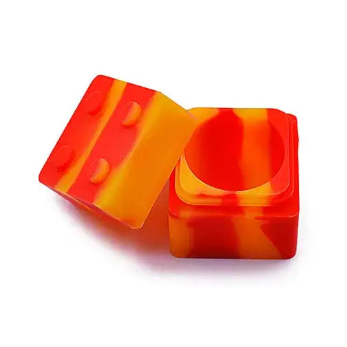 Two square silicone container pieces, one acting as a lid, in a vibrant red and orange swirled pattern, resembling a dice or building block.