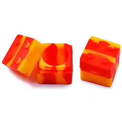 Three square silicone containers, two open and one closed, featuring a vibrant red and yellow swirled pattern, resembling toy building blocks.