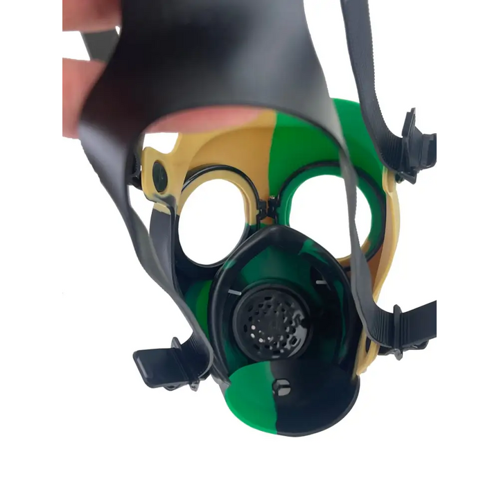 Inside view of a silicone gas mask bong, showing the green, black, and tan interior with eyeholes and a central filter.