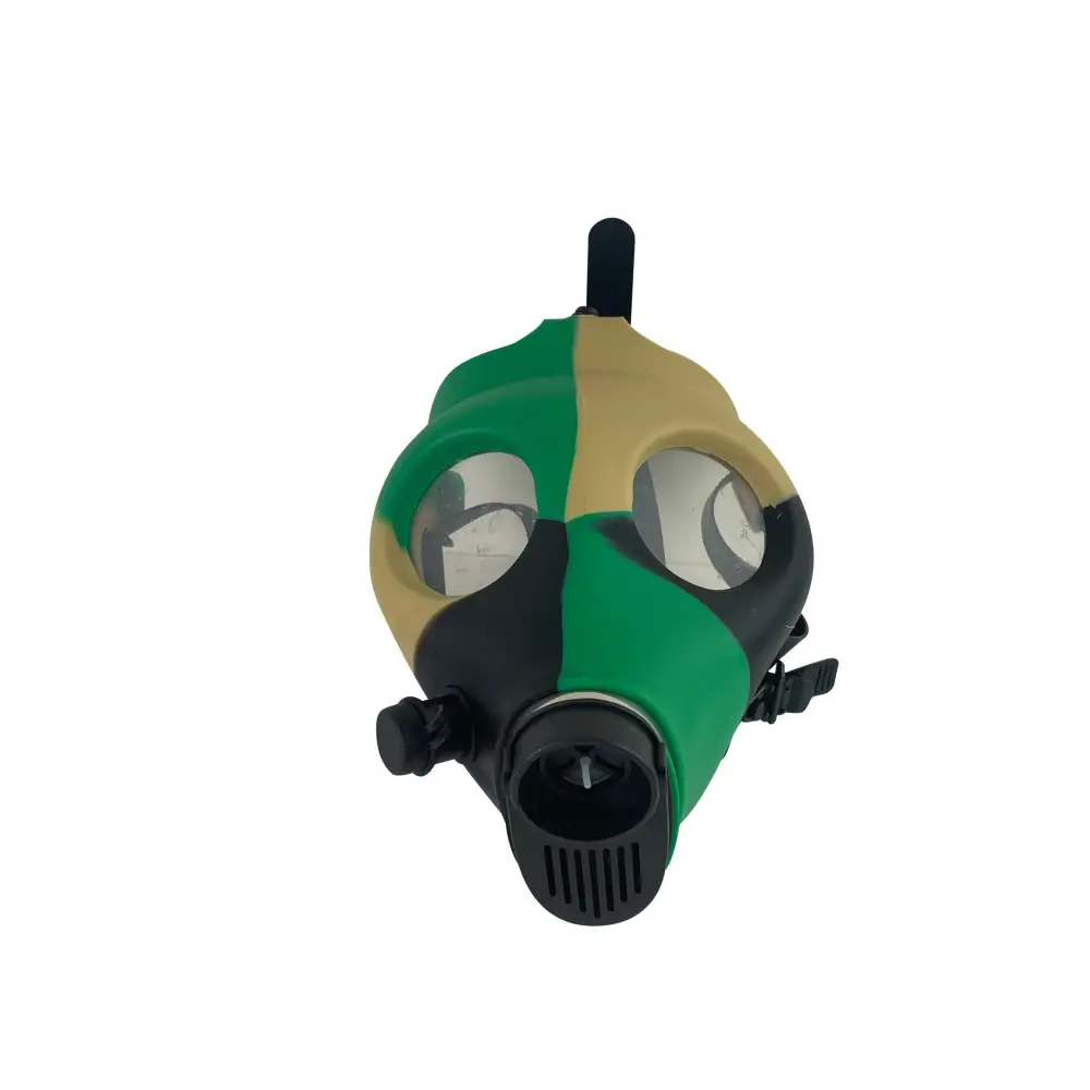 Front-facing view of a silicone gas mask bong, featuring a camouflage pattern in green, tan, and black, with clear eye lenses and a black mouthpiece.