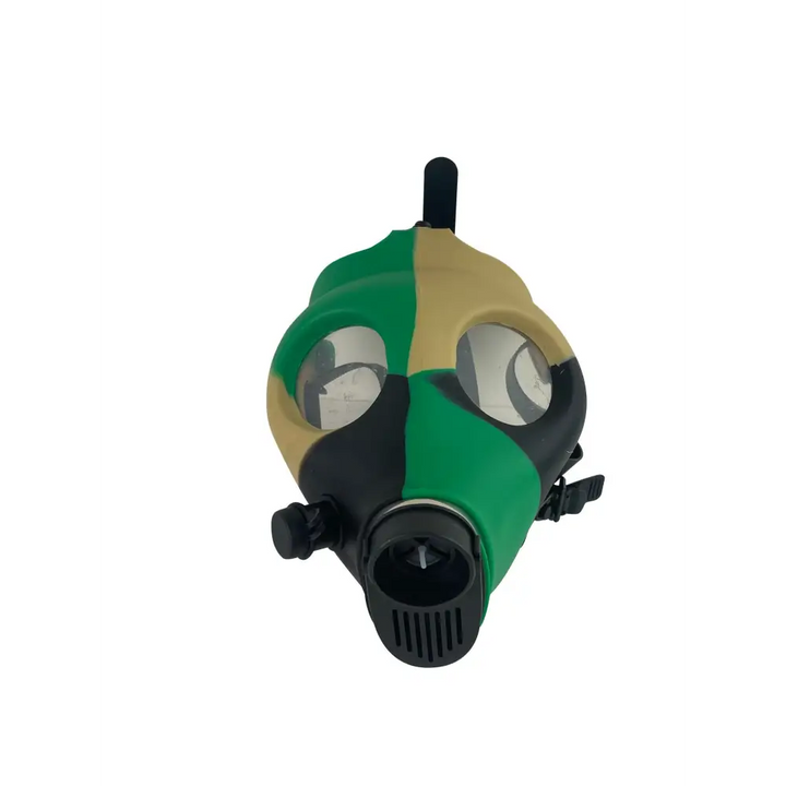 Front-facing view of a silicone gas mask bong, featuring a camouflage pattern in green, tan, and black, with clear eye lenses and a black mouthpiece.
