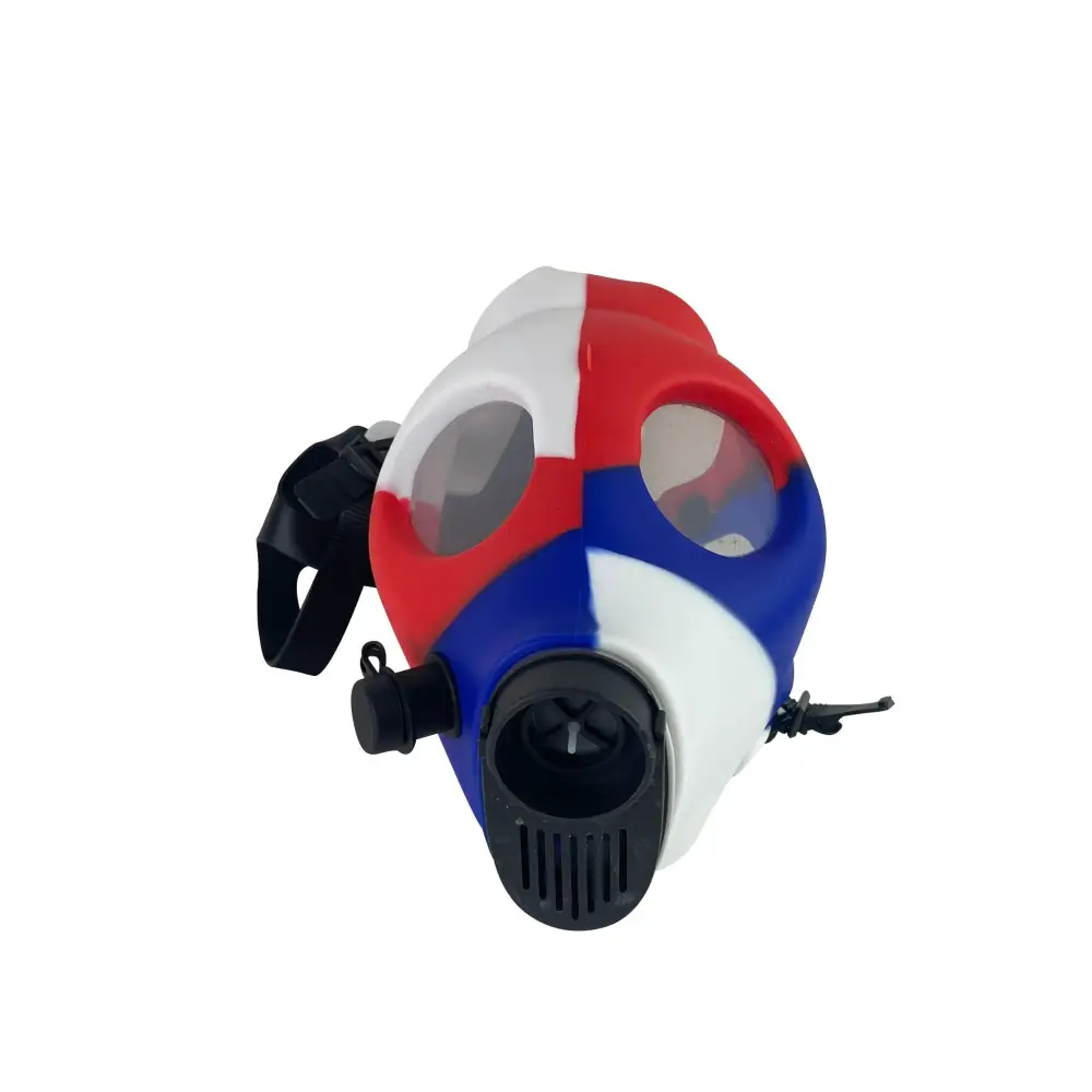 Close-up, slightly angled view of a silicone gas mask bong, featuring a patriotic red, white, and blue color scheme with clear eyeholes and a black filter attachment.