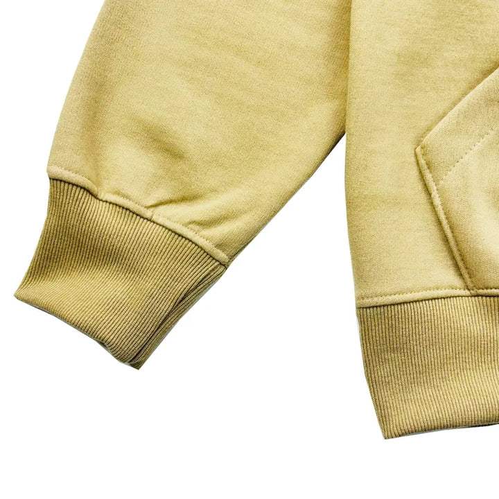 Close-up detail of a light brown hoodie's ribbed cuff and lower body, showcasing the fabric texture.