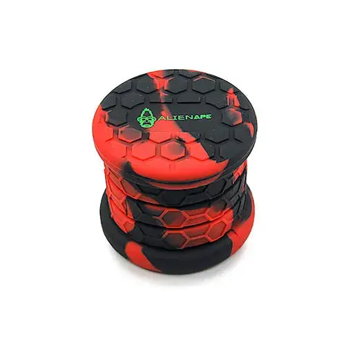 Close-up view of a red and black marbled collapsible silicone storage jar with a honeycomb texture and a green AlienApe logo on the lid.