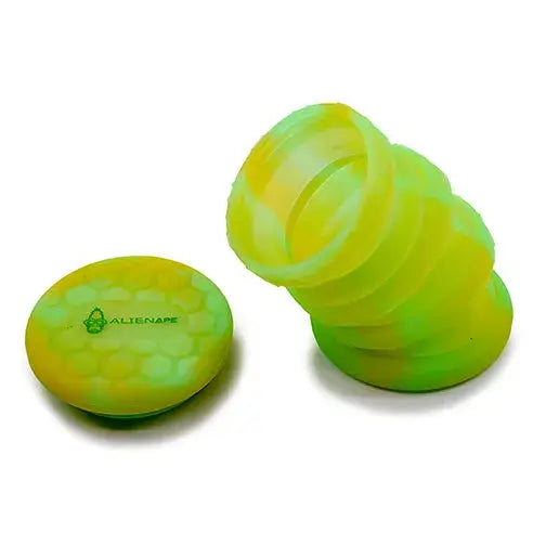 Two parts of a collapsible silicone jar in bright yellow-green and neon green. One part is collapsed and flat with a honeycomb pattern and 'ALIENAPE' logo, the other is extended in an accordion shape.