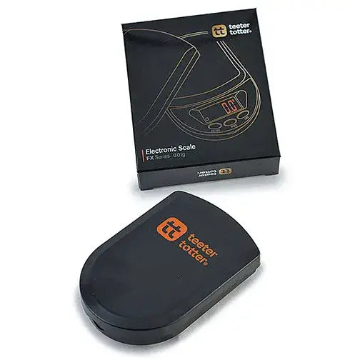 A black electronic scale with an orange 'teeter totter' logo rests next to its black packaging box, also featuring the brand logo and 'Electronic Scale FX Series - 0.01g' text, all against a white background.