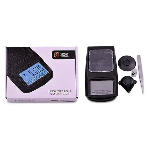 A black digital scale with a clear cover, its packaging box, and several small accessories including tweezers and calibration weights, are displayed on a white background.
