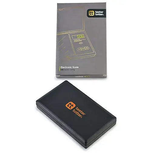 A black electronic scale with orange 'teeter totter' branding is displayed next to its gray packaging box, both resting on a clean white background.