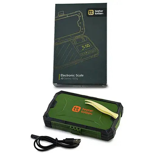 An electronic scale in its dark green and black packaging, with the scale itself, a USB charging cable, and small yellow tweezers laid out on a white background.