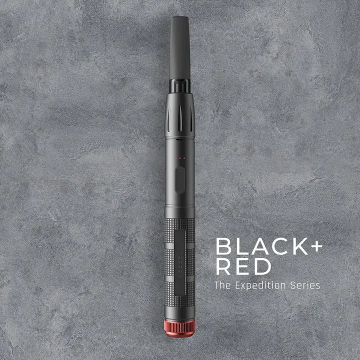 Top-down view of a black pen-style vaporizer with a red base, featuring textured grip sections and a small indicator light, against a dark gray textured background with 'BLACK + RED The Expedition Series' text.