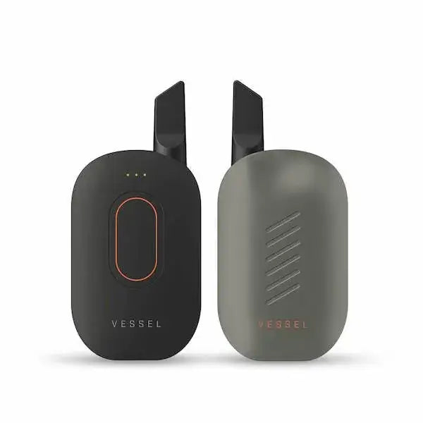 Two compact, oval-shaped cartridge batteries are shown side-by-side, one in dark gray/black with an orange accent, and the other in light gray with diagonal lines, both featuring black mouthpieces.