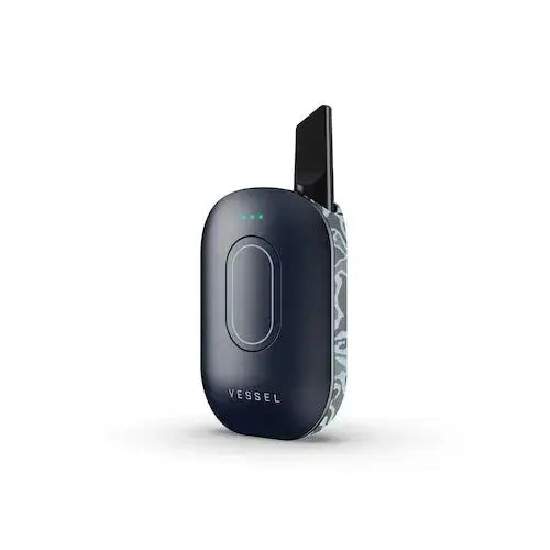 A dark navy blue, oval-shaped vaporizer battery stands upright, featuring a light grey abstract pattern on its right side and a black mouthpiece extending from the top. Three small green indicator lights are visible on the front.