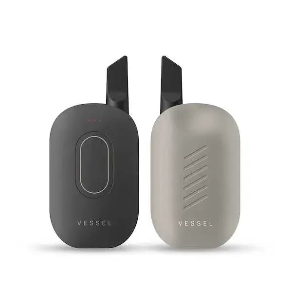 Two compact, rectangular vaporizers with rounded edges, one in dark gray and one in light gray, both featuring black angled mouthpieces and the 'VESSEL' logo.