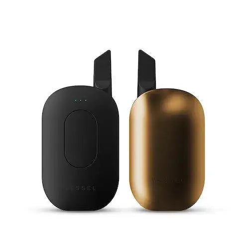 Two compact, rounded rectangular vaporizers, one matte black and one metallic gold, standing upright side-by-side against a white background, showcasing color variants.