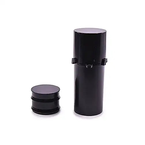 A black, cylindrical herb grinder is shown disassembled on a white background. The taller main body stands upright, while the shorter grinding chamber rests beside it.